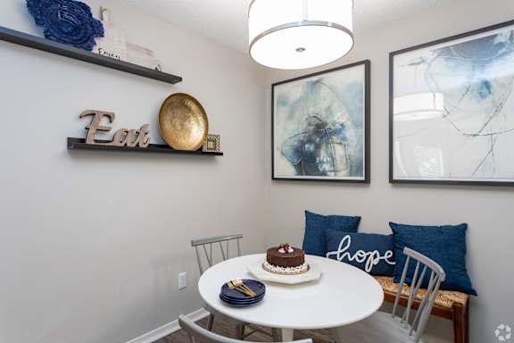A dining room with a white table and a cake on it.