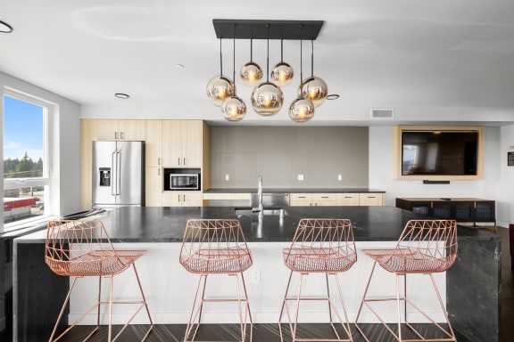 a modern kitchen with copper bar stools and a large island at Ion Town Center, Shoreline, WA