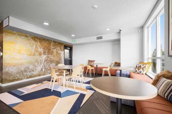 a seating area with tables and chairs and a large mural on the wall at Ion Town Center, Washington, 98133