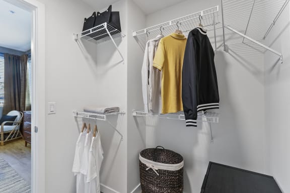 Walk in closet with a rack of clothes and a basket at The Lofts at Carlsbad Village, Carlsbad, California