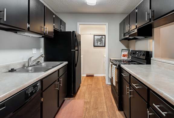 A kitchen with black cabinets and a white refrigerator.