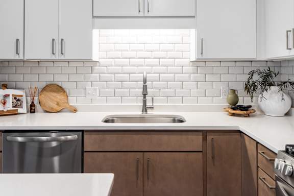 A kitchen with a white sink and brown cabinets.