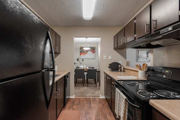 A kitchen with black appliances and wooden floors.