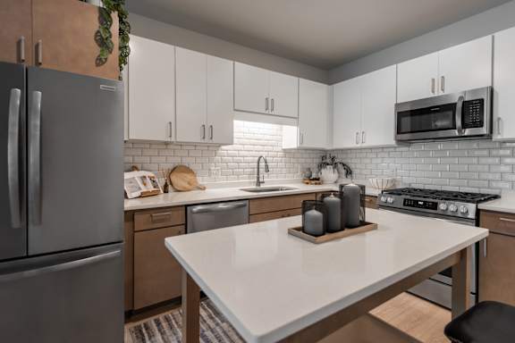 A kitchen with a white countertop and a stainless steel refrigerator.