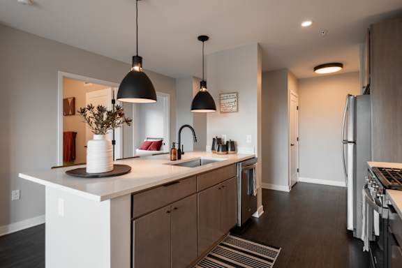 A modern kitchen with a white countertop and wooden cabinets.