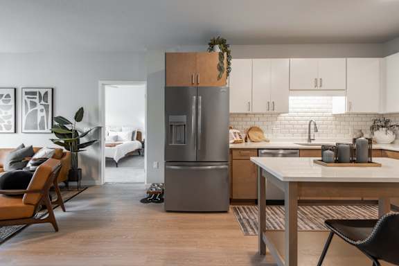 A modern kitchen with a refrigerator, sink, and dining table.