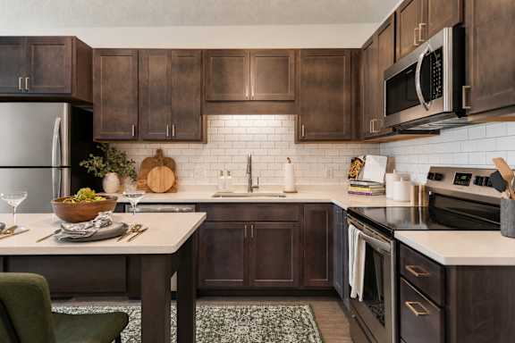 A kitchen with dark brown cabinets and a white countertop.
