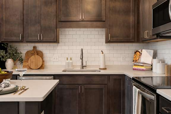 A kitchen with dark brown cabinets and a white countertop.