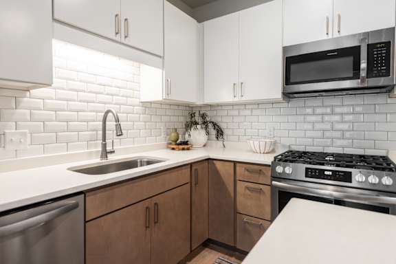 A modern kitchen with a stainless steel dishwasher and a white countertop.