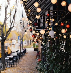 a sidewalk in front of a restaurant with christmas lights on it