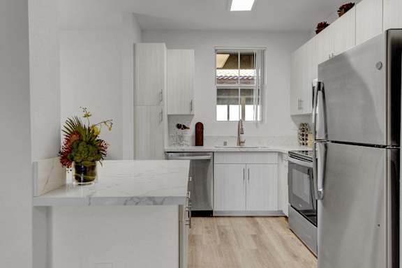a kitchen with white cabinets and stainless steel appliances and a marble counter top