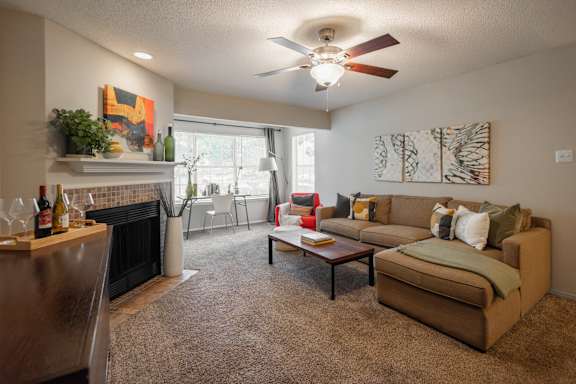A living room with a fireplace, couch, and a ceiling fan.