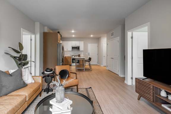 A modern living room with a glass coffee table and a flat screen TV.