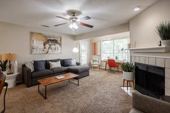 A living room with a grey couch, a coffee table, a fireplace, and a painting of a horse on the wall.