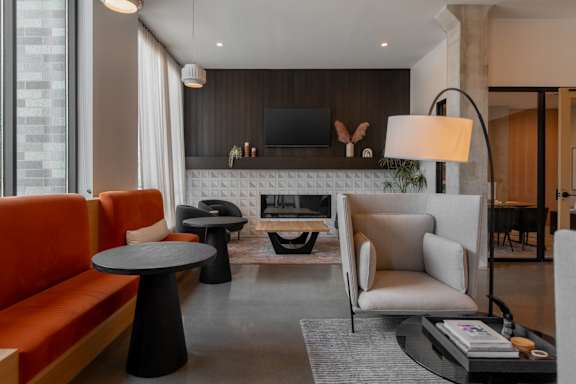 A modern living room with a grey rug, a black table, a white sofa, and a TV on the wall.