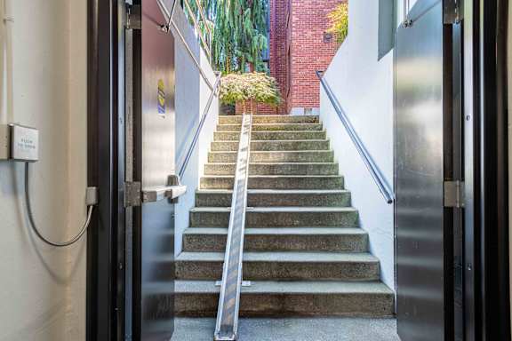A set of stairs with a metal handrail leading to a door.