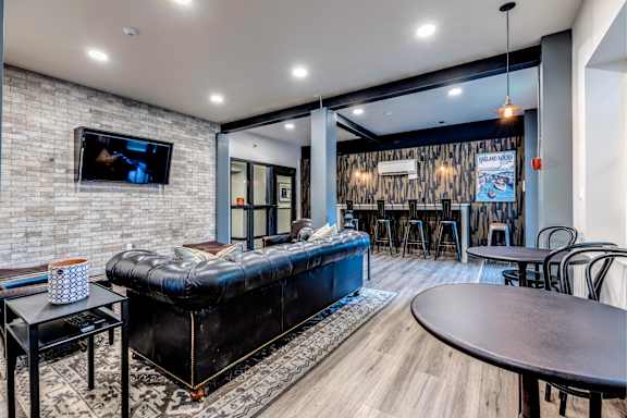 A modern living room with a black leather sofa and a flat screen TV mounted on a brick wall. at Lock Vista, Seattle