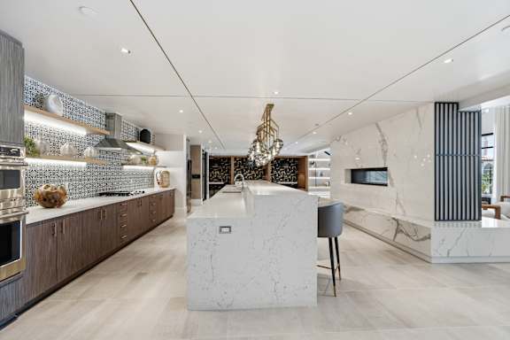 A modern kitchen with a marble island and wooden cabinets.
