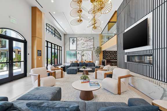 A modern living room with a large sofa set and a TV on the wall.