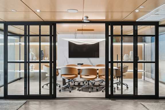 A conference room with a table and chairs is visible through a glass door.