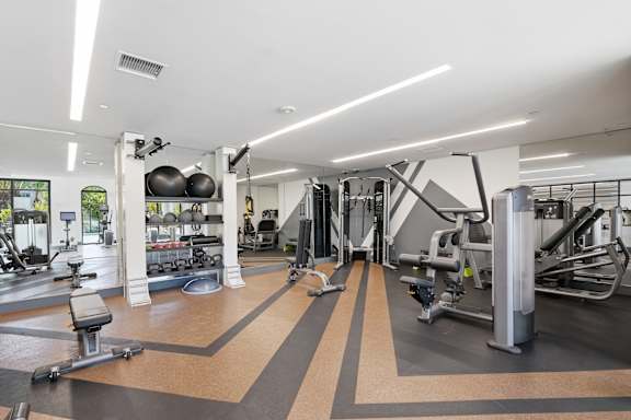 A gym with a variety of equipment including treadmills, weights, and exercise machines.