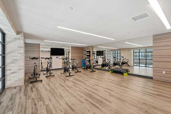 A gym with wooden floors and a variety of exercise equipment.