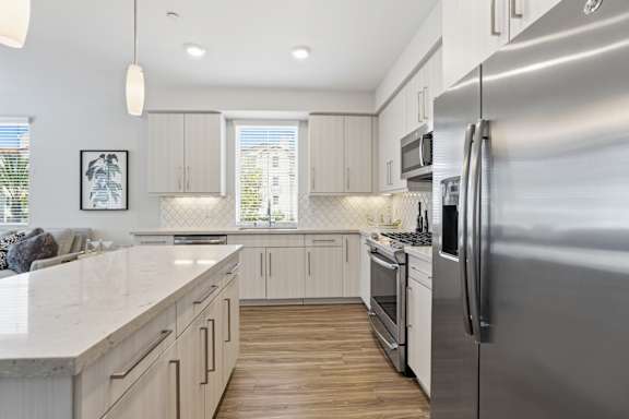 A modern kitchen with a stainless steel refrigerator and wooden floors.