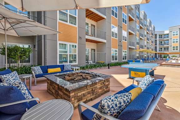 A patio with a fire pit and chairs.