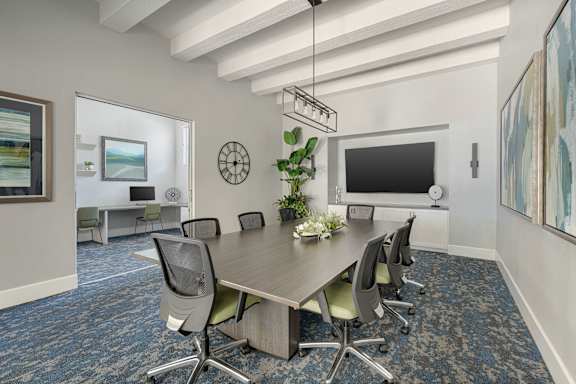 A conference room with a long table surrounded by chairs.