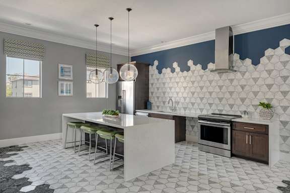 A kitchen with a white island and a black and white floor.