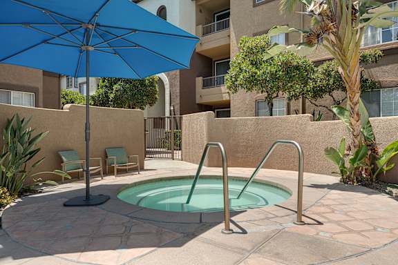A blue umbrella is next to a pool in a courtyard.