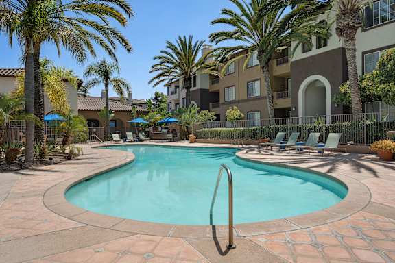 A swimming pool surrounded by palm trees and lounge chairs.