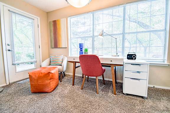 A room with a desk, chair, and window.
