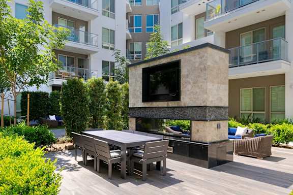 A modern outdoor entertainment area with a television and seating.
