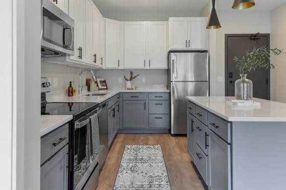 A kitchen with white cabinets and a grey refrigerator.