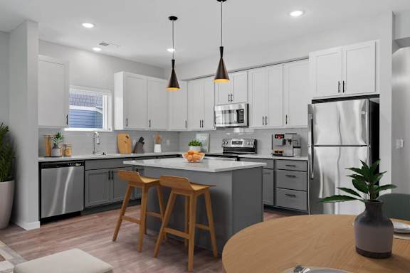 A modern kitchen with a central island and wooden stools.