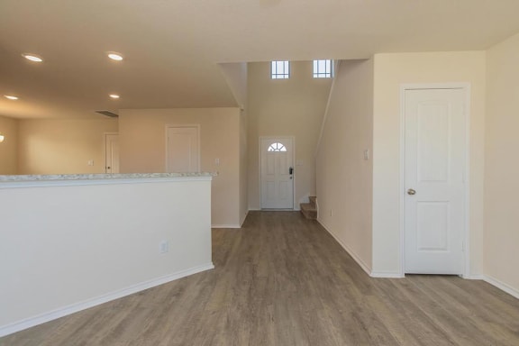 an empty living room and kitchen with a door to a hallway