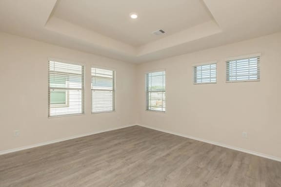 an empty living room with a wood floor and windows
