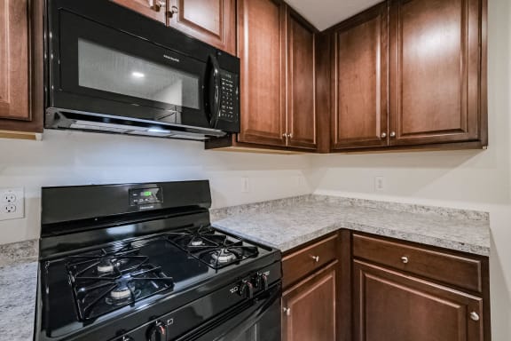 a kitchen with a stove and microwave and wooden cabinets
