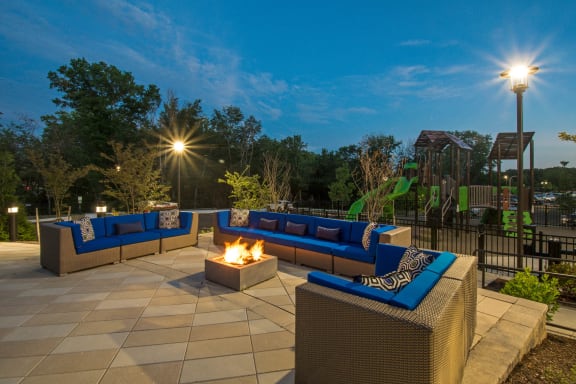 a patio with couches and a fire pit at night