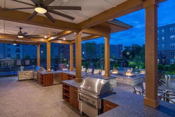 a covered patio with a grill and a spa at night