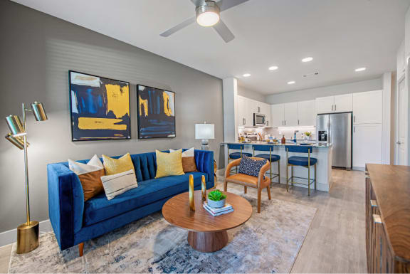 a living room and kitchen with a blue couch and a table
