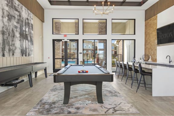 a pool table in a game room with a bar and tables