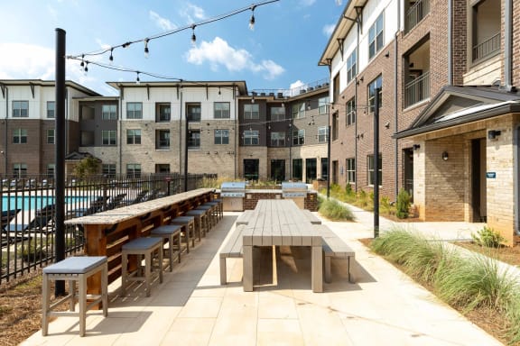 an outdoor patio with tables and benches at a building with a pool
