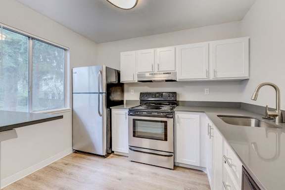 A kitchen with white cabinets and a stainless steel refrigerator.