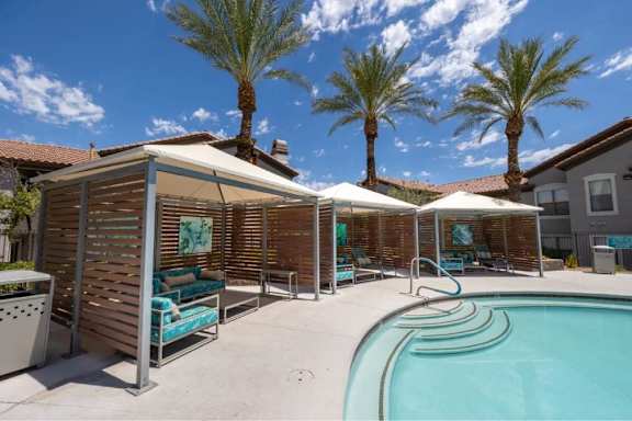 A pool area with a wooden fence and palm trees.