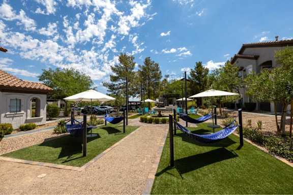 A sunny day at a park with hammocks and umbrellas.