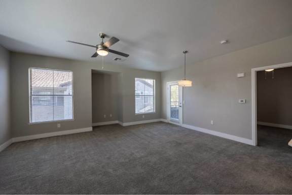 A spacious room with a ceiling fan and carpeted floor.