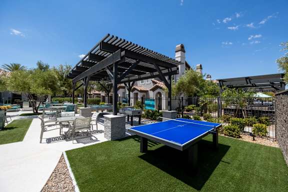 A blue table tennis table is in the middle of a grassy area.