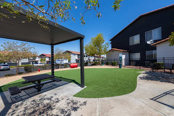 A black and white picnic table is in the middle of a green lawn.